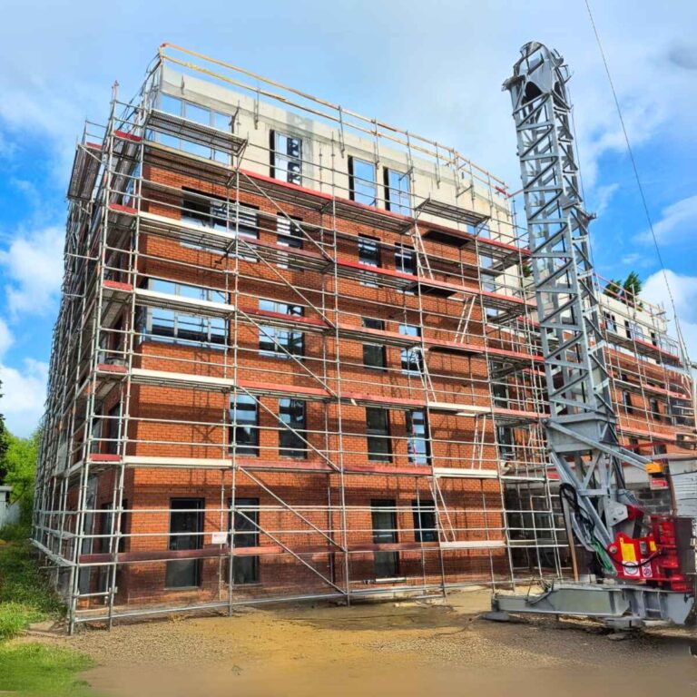 Construction d'un immeuble à appartements en briques rouges avec des échafaudages